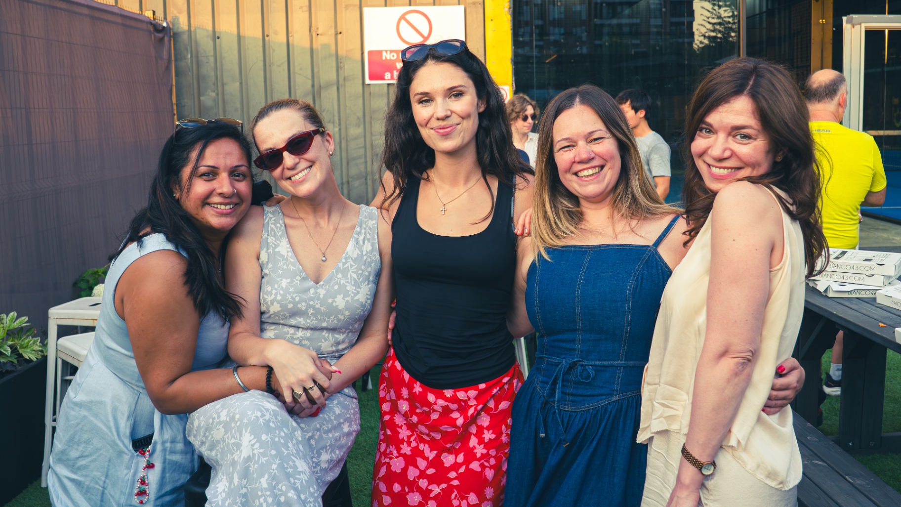 Group of guests laughing together at a Padel Fiesta social after matches