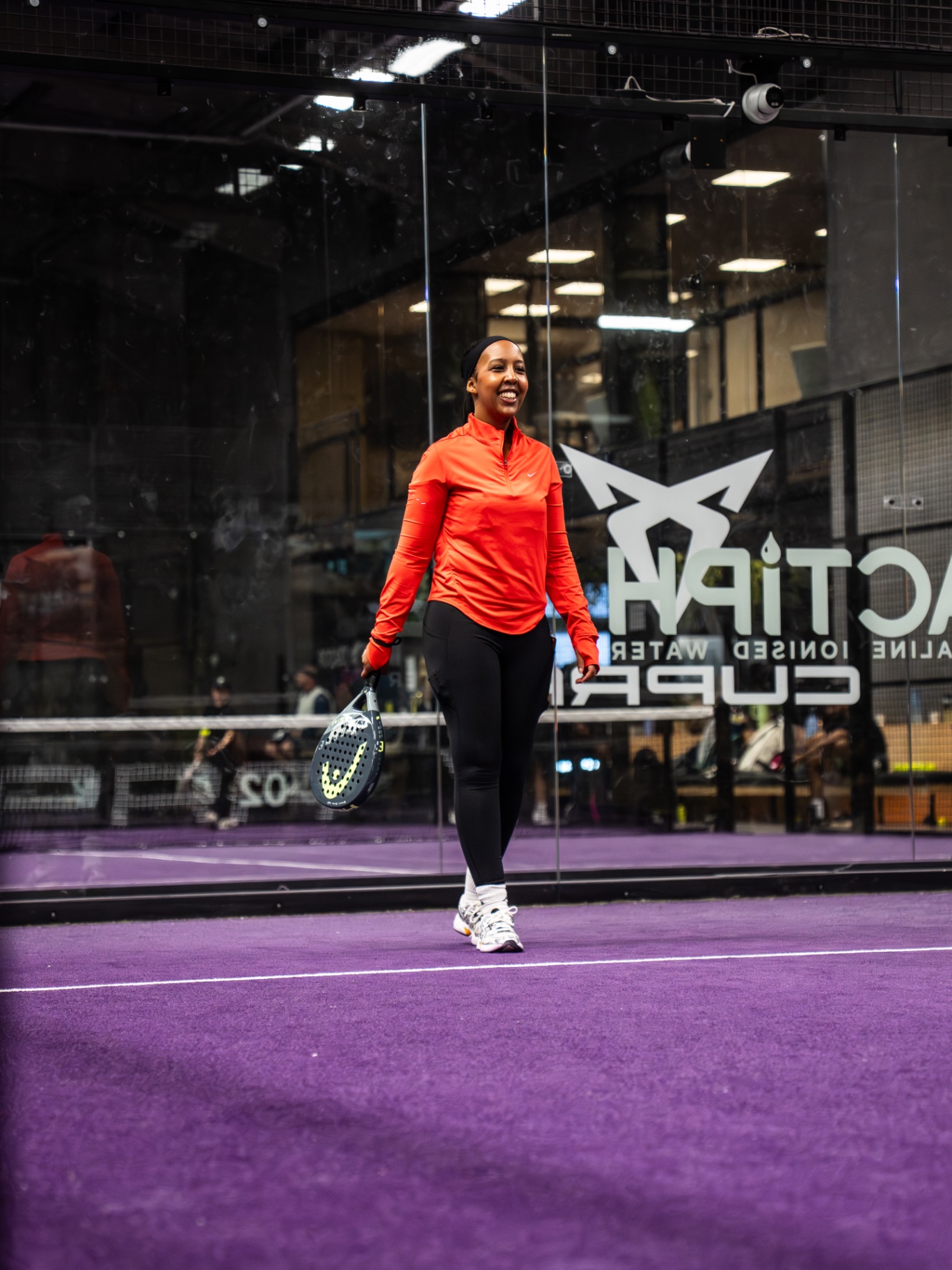Guest walking onto the court smiling, racket in hand